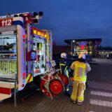 Feuerwehrkräfte stehen an ihrem Einsatzfahrzeug.