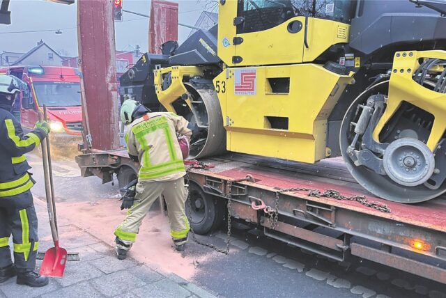Die Feuerwehr streut eine Öllache an einem Tieflader ab.