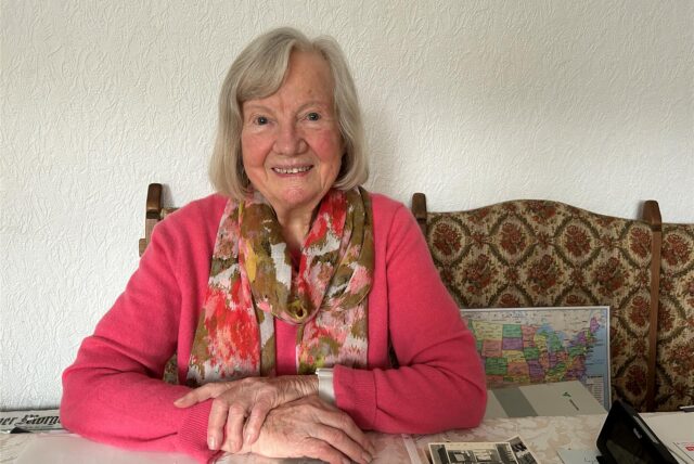 Renate Bystron sitzt an ihrem Esstisch, vor sich Fotos und Dokumente.