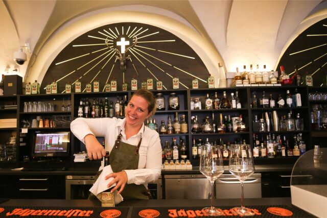 Eine Mitarbeiterin vom Dortmunder Restaurant Emil Grill & Meer steht hinter der Theke und öffnet eine Weinflasche