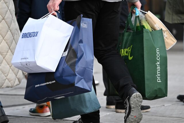 Ein Mann geht am verkaufsoffenen Sonntag mit Tüten bepackt shoppen.