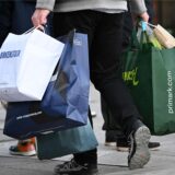 Ein Mann geht am verkaufsoffenen Sonntag mit Tüten bepackt shoppen.