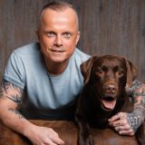Thorsten „Toto“ Habel aus Dortmund und Assistenzhündin Hanni posieren in einem Fotostudio.