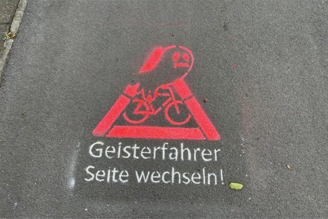 Piktogramm mit der Aufschrift „Geisterradler Seite wechseln“ auf einem Radweg