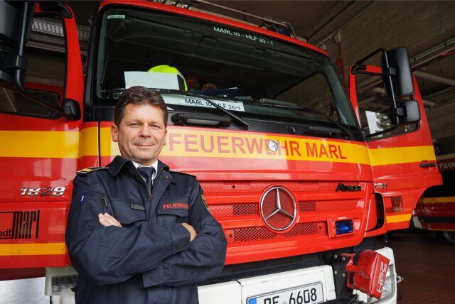Oberbrandrat Rainald Pöter steht vor einem Auto der Marler Feuerwehr.