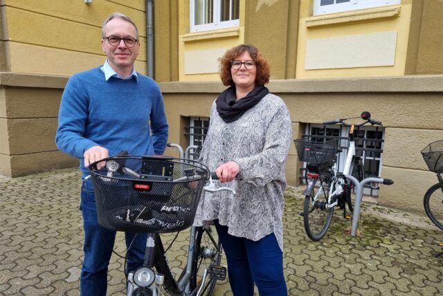 Ein Mann und eine Frau stehen an einem Fahrrad vor dem Dattelner Rathaus.
