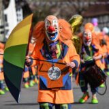 Ein Mensch steht als Clown verkleidet auf einer Straße.