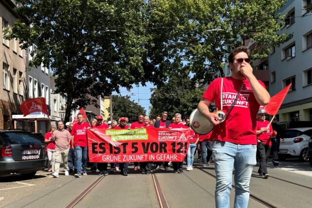 Ein Mann mit einem T-Shirt mit der Aufschrift „Stahl ist Zukunft“ und einem Megafon in der Hand läuft vorneweg. Im Hintergrund folgt eine Demonstration der Gewerkschaft IG Metall. Bereits im Sommer hatte die Gewerkschaft in Dortmund demonstriert.