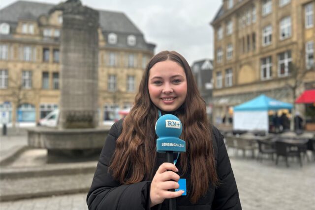 Redakteurin Tabea Bremer steht mit einem Ruhrnachrichten-Mikrofon auf dem Marktplatz in der Castroper Altstadt.