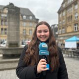 Redakteurin Tabea Bremer steht mit einem Ruhrnachrichten-Mikrofon auf dem Marktplatz in der Castroper Altstadt.