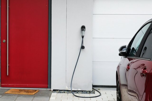 Ein Elektroauto steht vor einer Wandladestation, die zwischen Garagentor und Haustür angebracht ist. In Recklinghausen ist Netzbetreiber Westnetz für die Anmeldung einer „Wallbox“ zuständig.