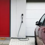 Ein Elektroauto steht vor einer Wandladestation, die zwischen Garagentor und Haustür angebracht ist. In Recklinghausen ist Netzbetreiber Westnetz für die Anmeldung einer „Wallbox“ zuständig.