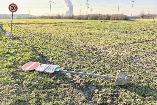 Ein Verkehrsschild liegt auf einem Acker.