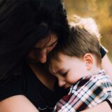Eine Mutter hält ihren Sohn im Arm und tröstet ihn.