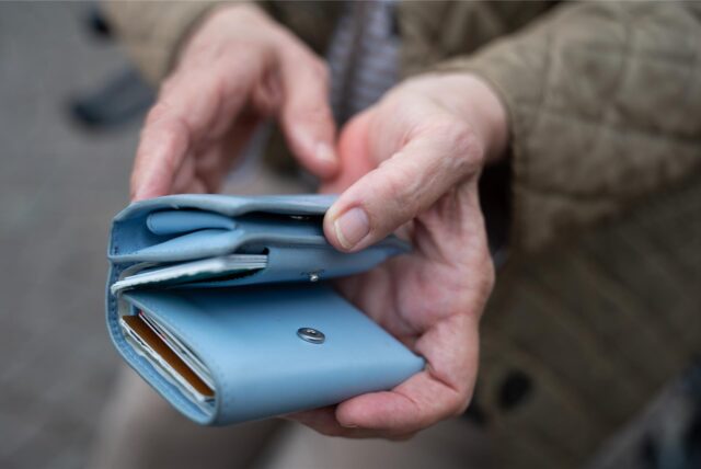 Eine Frau hält ein Portemonnaie in der Hand.