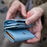 Eine Frau hält ein Portemonnaie in der Hand.
