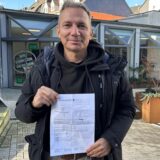 Jens Schneeweiß mit einem Dokument, das bescheinigt, dass sein Ausweis von der Stadt angenommen wurde.