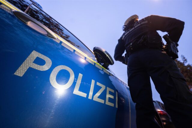 Eine Polizistin steht neben einem Polizeiauto.  (Symbolbild)