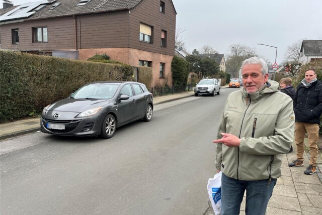 Christian Friedrich, Vorsitzender der Siedlergemeinschaft Herten-Süd, deutet an der Königsberger Straße auf einen vorbeifahrenden grauen Pkw.