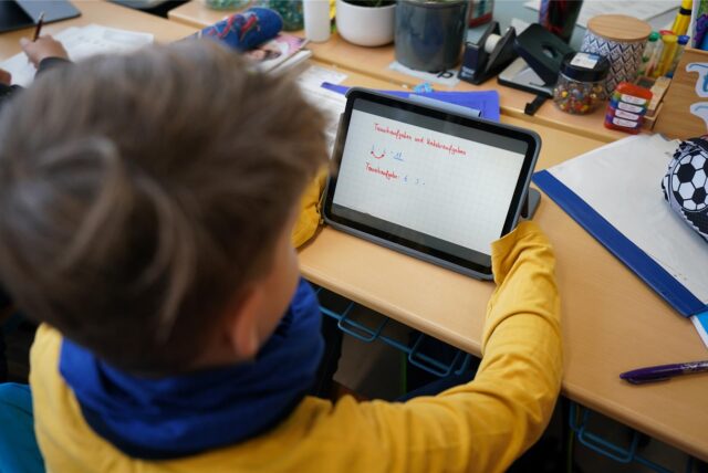 Schüler sitzt mit einem Tablet im Unterricht.
