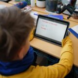 Schüler sitzt mit einem Tablet im Unterricht.