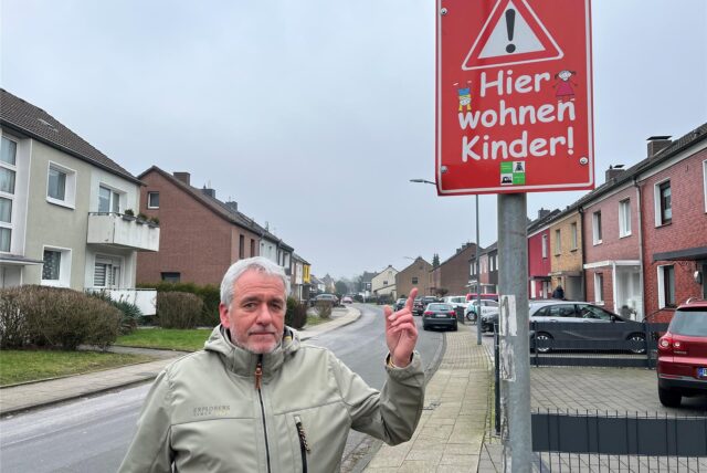 Christian Friedrich steht an der Königsberger Straße und deutet mit dem Zeigefinger auf ein rotes Schild.