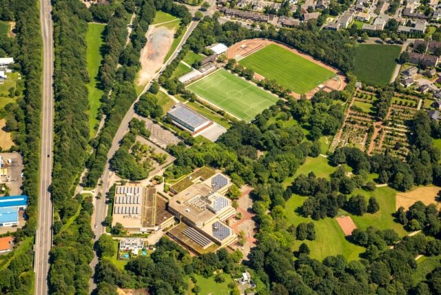 Das Luftbild zeigt die Rosa-Parks-Schule am Rande von Herten-Disteln im Grünen. Daneben ist der schnurgerade Autobahnzubringer L 511 zu sehen.