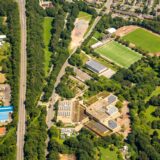 Das Luftbild zeigt die Rosa-Parks-Schule am Rande von Herten-Disteln im Grünen. Daneben ist der schnurgerade Autobahnzubringer L 511 zu sehen.