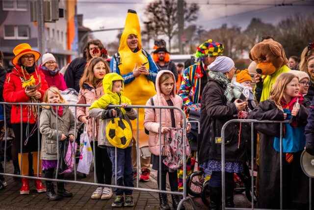 Kinder und Eltern in bunten Kostümen beim Rosenmontagszug in Dortmund.