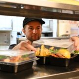 Küchenchef reicht Mehrweggeschirr über die Theke