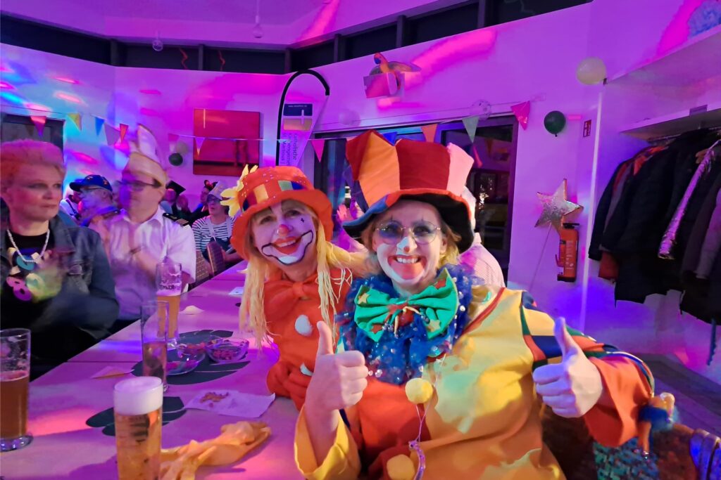 Zwei als Clowns verkleidete Frauen sitzen bei der Karnevalsparty 2024 der Gemeinde St. Martinus in Herten-Westerholt an einem Tisch. Zwei als Clowns verkleidete Frauen sitzen bei der Karnevalsparty 2024 der Gemeinde St. Martinus in Herten-Westerholt an einem Tisch.
