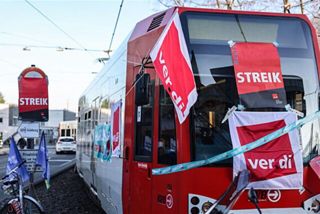 Eine mit Streik-Plakaten beklebte Straßenbahn der Kölner Verkehrs-Betriebe (KVB) steht vor dem Bahndepot.
