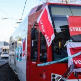 Eine mit Streik-Plakaten beklebte Straßenbahn der Kölner Verkehrs-Betriebe (KVB) steht vor dem Bahndepot.
