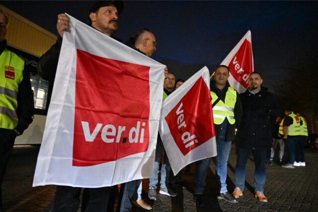 Verdi-Mitglieder bei einem Warnstreik mit Fahnen in der Hand.