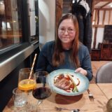 Eine Frau hält einen Teller mit Fleisch in die Kamera
