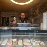 Inhaber Adim Ulupinar hält hinter der Eistheke des Café Laren in Marl-Hüls eine Waffel mit einer Kugel Eis in der Hand.