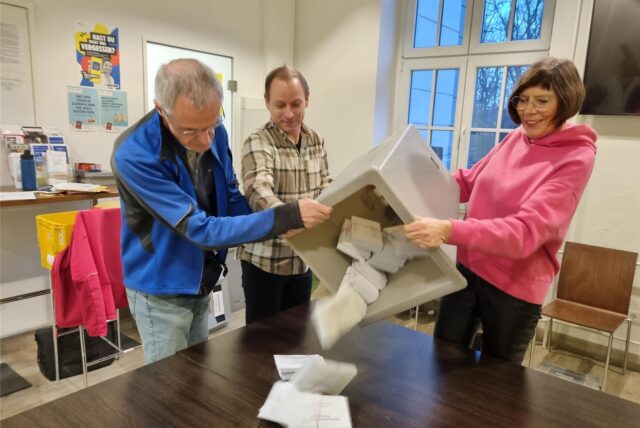 Drei Personen schütten eine Wahlurne aus.