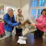 Drei Personen schütten eine Wahlurne aus.