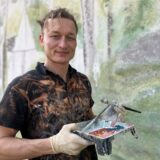 Künstler Juri Schäffer steht vor seinem Kunstwerk an der Wilhelm-Lehmbruck-Schule in Deuten.