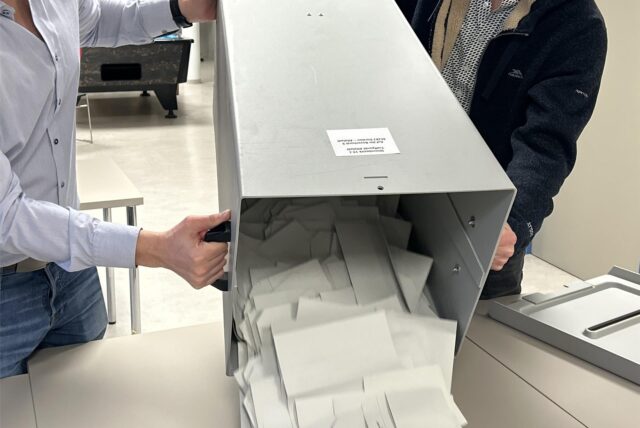 Zwei Menschen kippen eine Wahlurne aus.