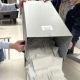 Zwei Menschen kippen eine Wahlurne aus.