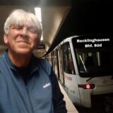 Franz-Josef Hauke steht auf dem Gleis neben einer einfahrenden Straßenbahn.