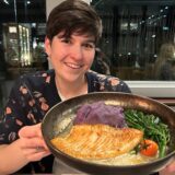 Jessica Will hält einen Teller mit ihrem Hauptgericht in die Kamera: Steinbuttfilet mit lilafarbenem Kartoffelstampf, Brokkoli und Tomaten.