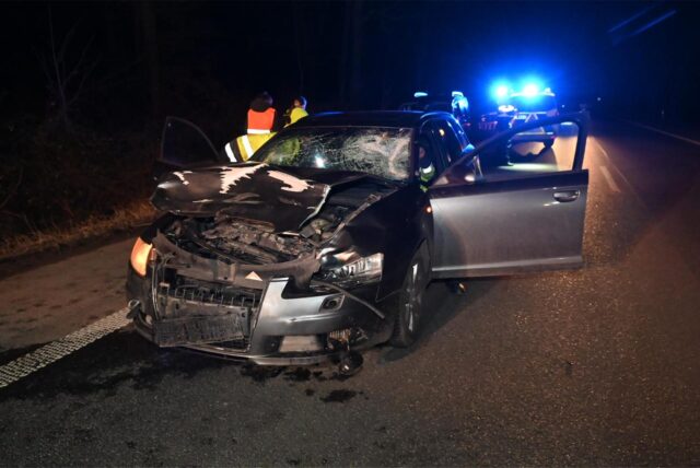 Ein schwer beschädigtes Auto mit Blaulicht im Hintergrund