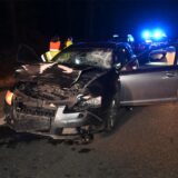 Ein schwer beschädigtes Auto mit Blaulicht im Hintergrund