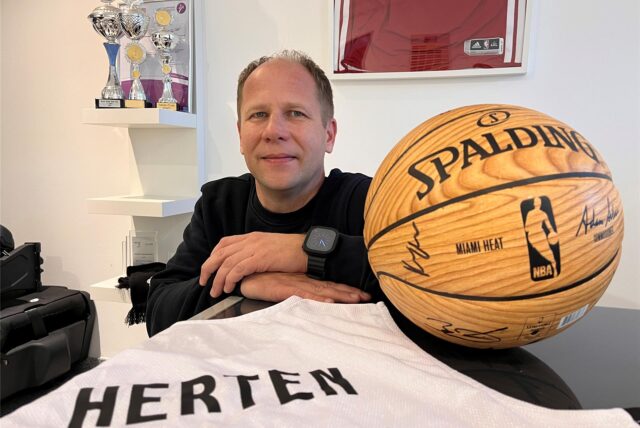 Klaus Prüsener neben einem Ball der Miami Heats, die von einem ehemaligen Hertener Spieler trainiert werden.