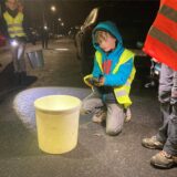 Ein Junge kniet auf der Jägerstraße in Herten vor einem Eimer. In seinen Händen hält er eine Kröte, die er vorsichtig in den Eimer legen wird.