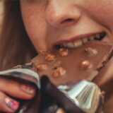 Frau beißt in Tafel Schokolade