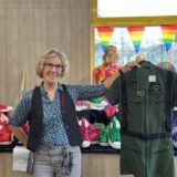 Filialleiterin Claudia Kadach hält lachend ein Kostüm hoch.