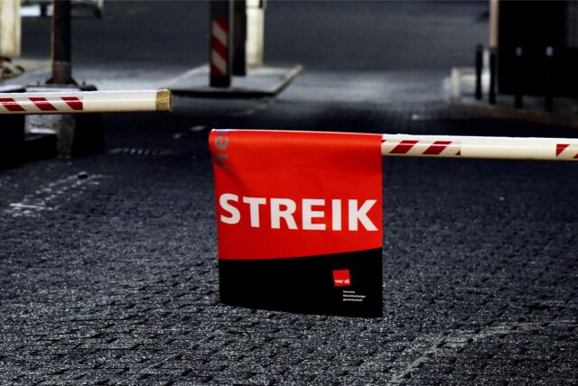 Eine Schranke ist geschlossen, daran hängt ein Plakat auf dem steht „Streik“